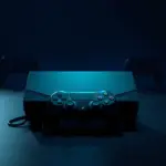 Dark gaming console with green rim lighting and a controller, with two rival console silhouettes fading into shadow in the background